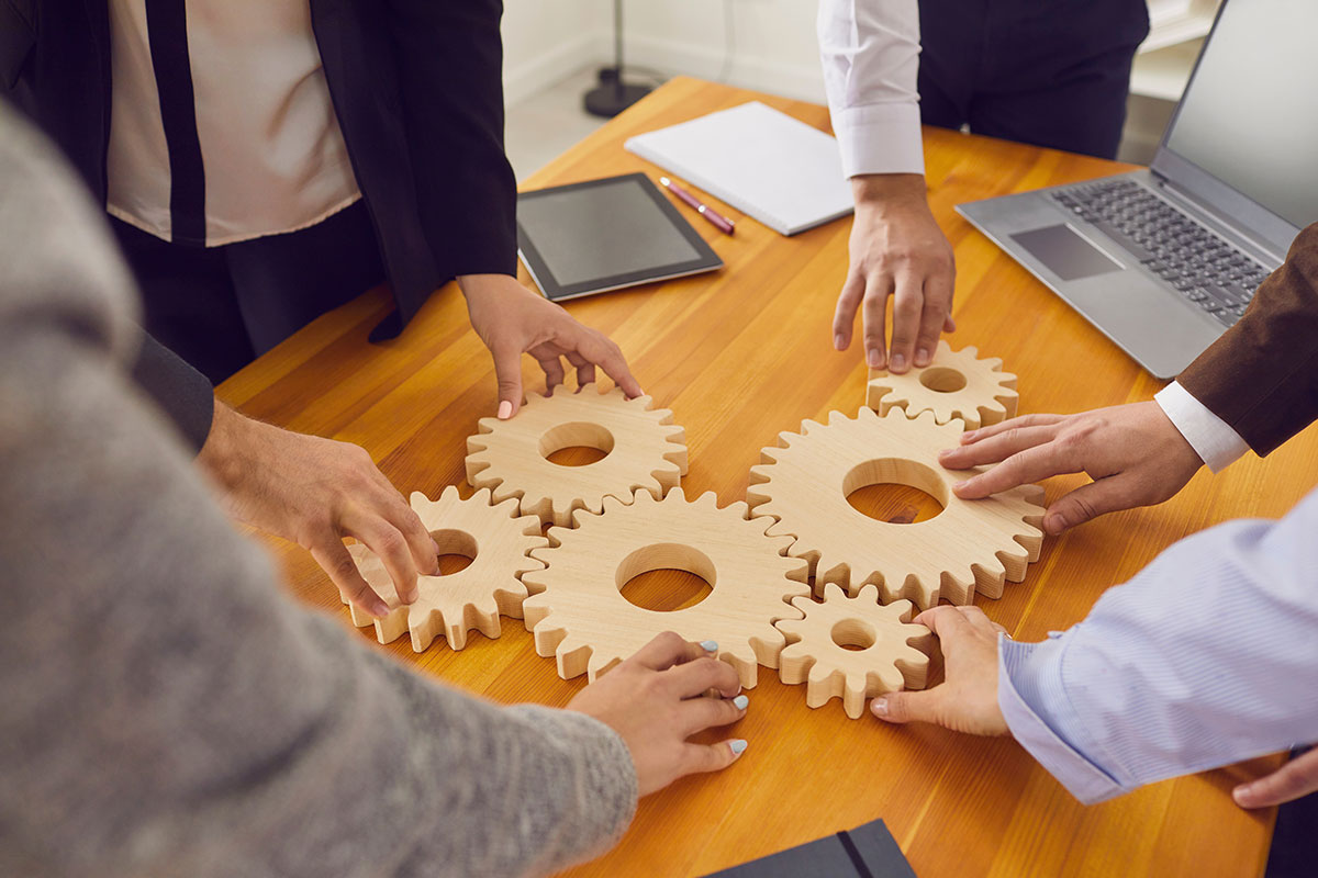 cogs on a table being turned by different hands showing integration