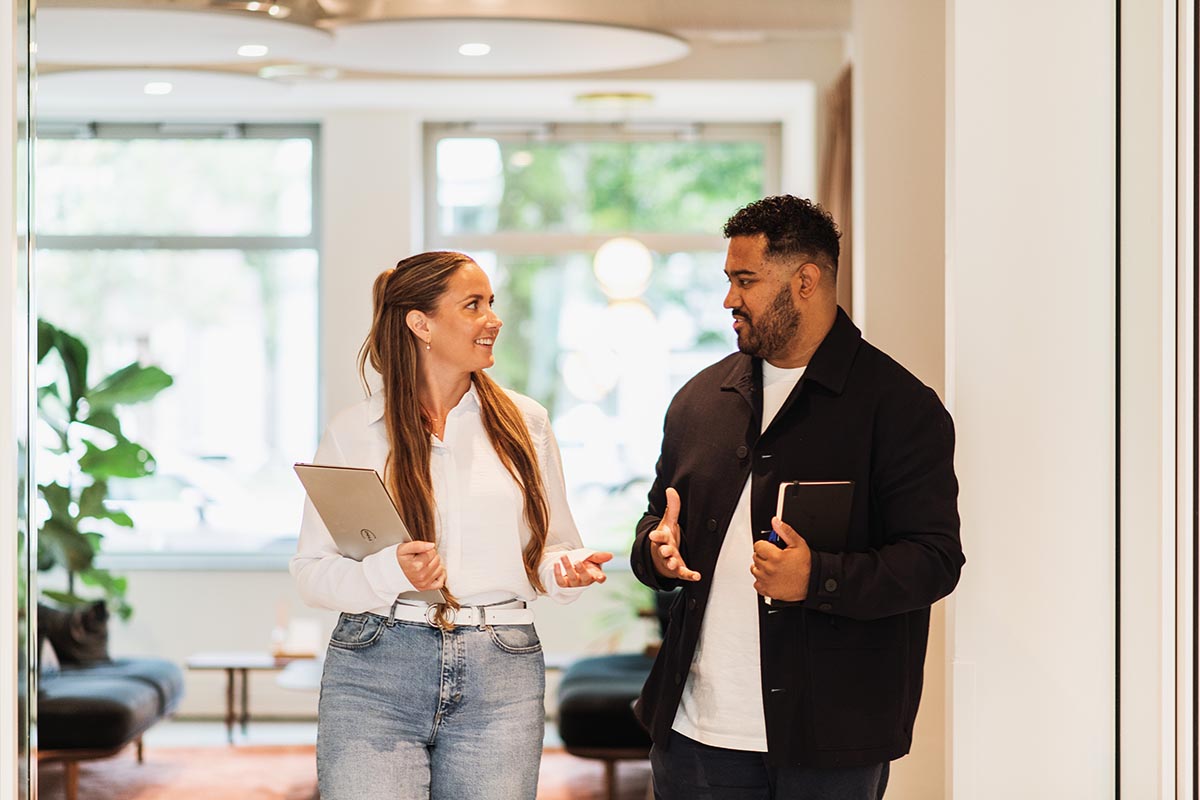 A woman and a man in an office corridor talking about background checks