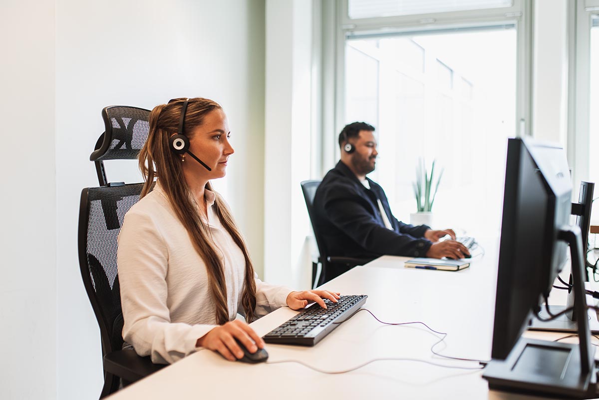 Man and woman conducting background checks at separate computers in an office environment