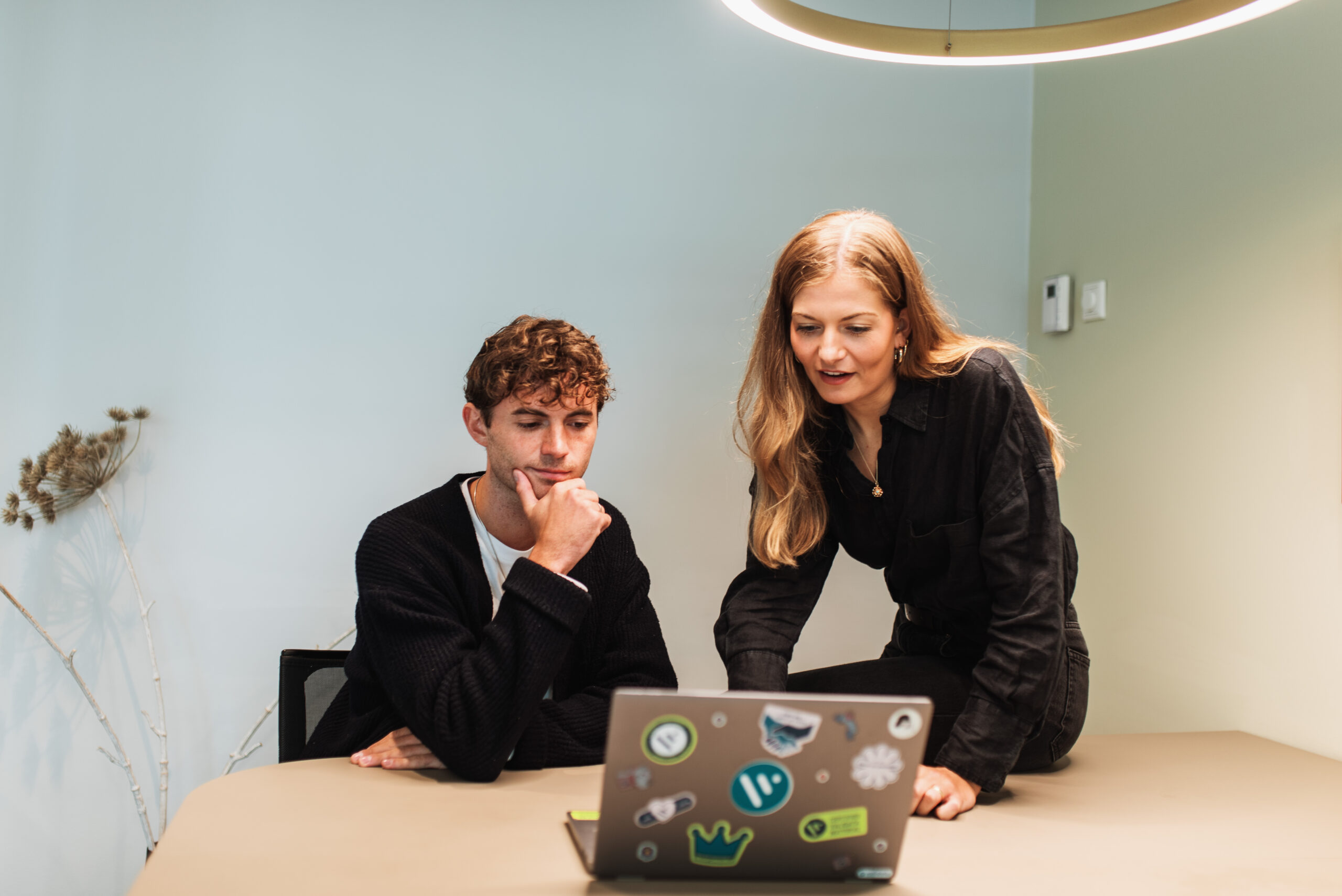 Twee collega's die op kantoor aan een laptop werken