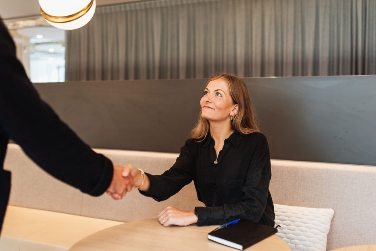 Woman shaking hands with a person out of frame in a modern Scandinavian office.