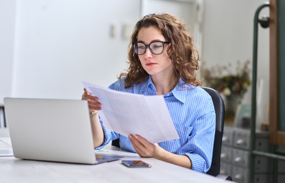 Women with glasses sitting in front of a computer looking at papers