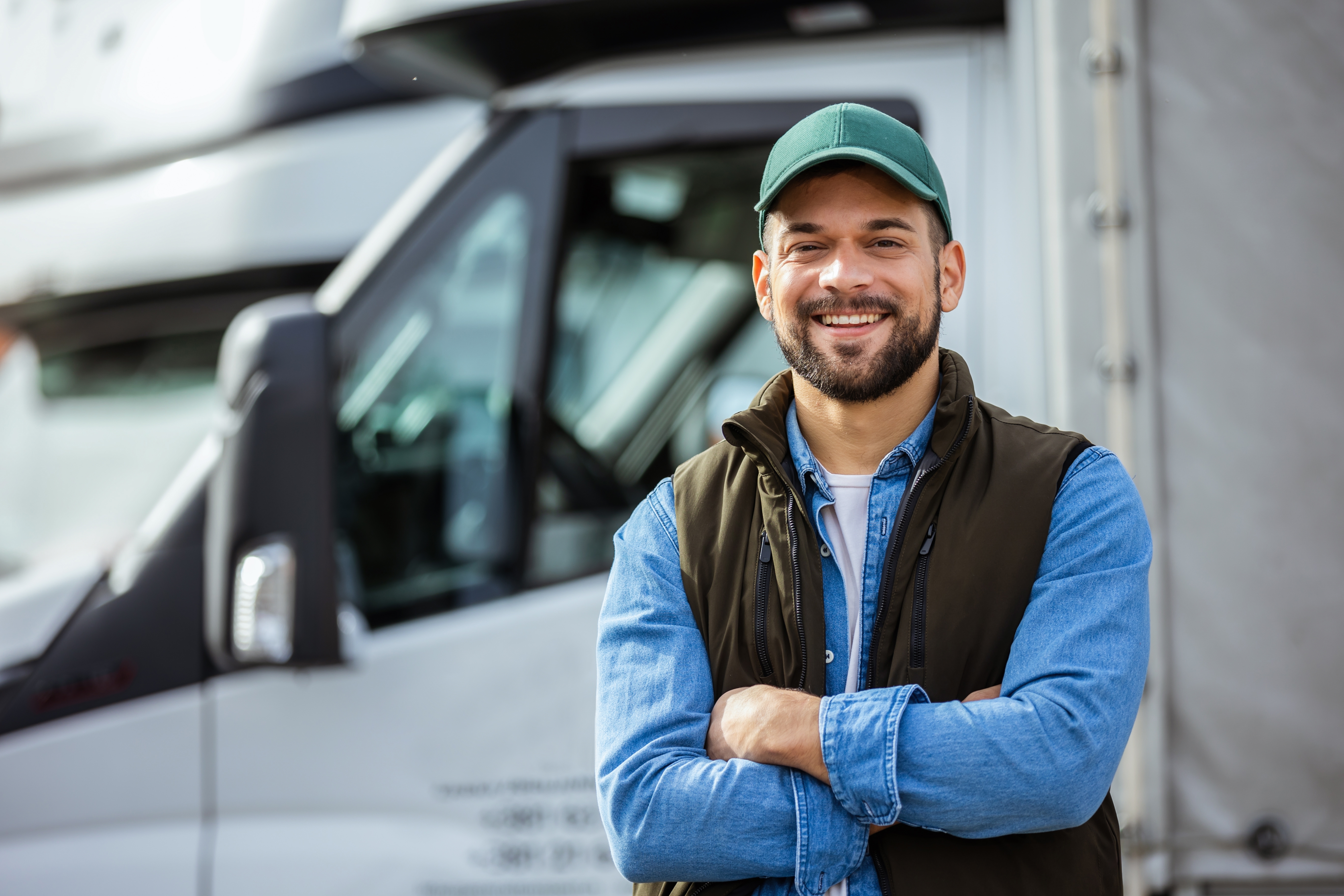 Happy worker standing in front of a truck