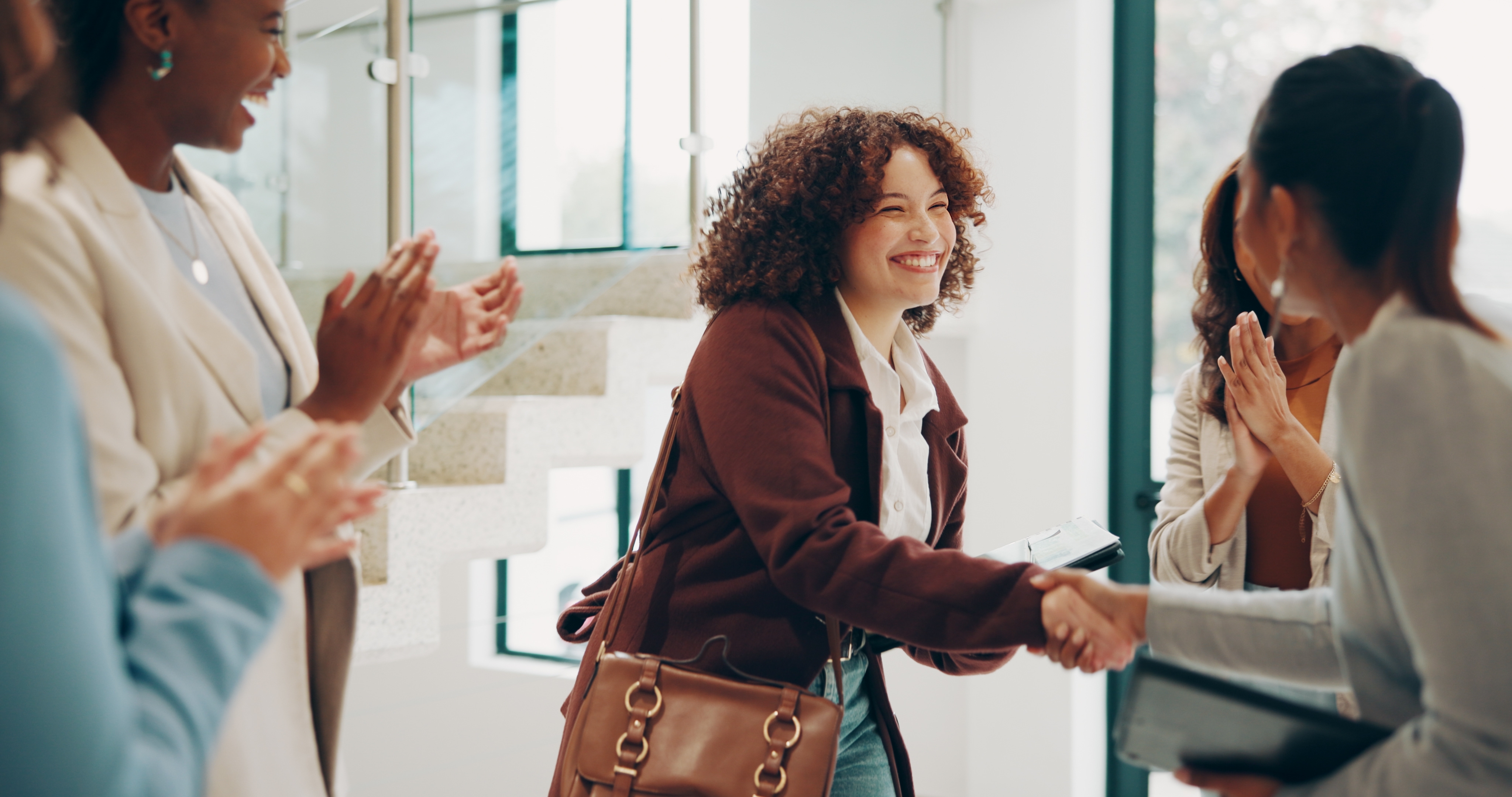 A woman shakes hands with another woman while holding a printed background check report