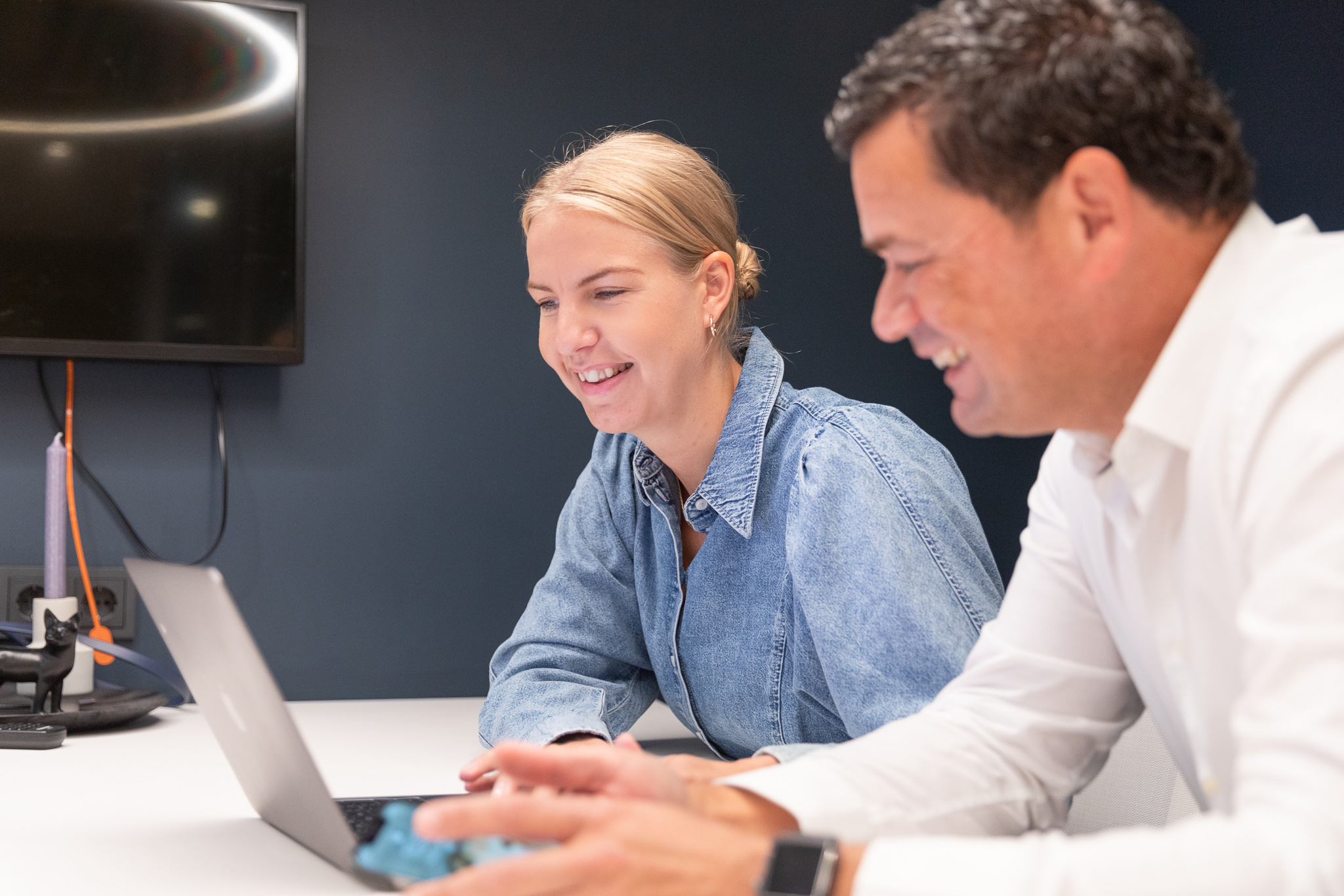 Man and women sitting in a blue painted room in front of a computer