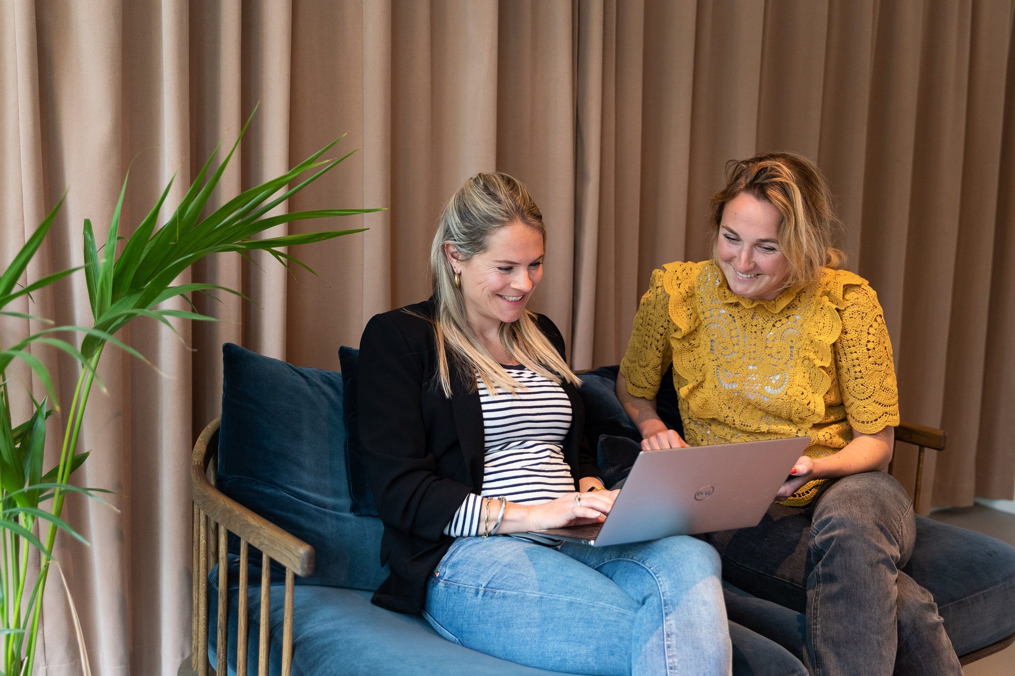 Two women sitting in a sofa looking at a computer