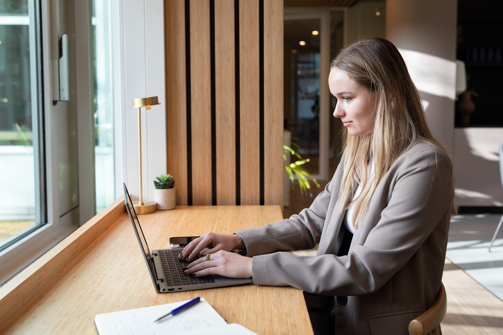 Young woman in a scandinavian office enviroemt sitting in front of a computer