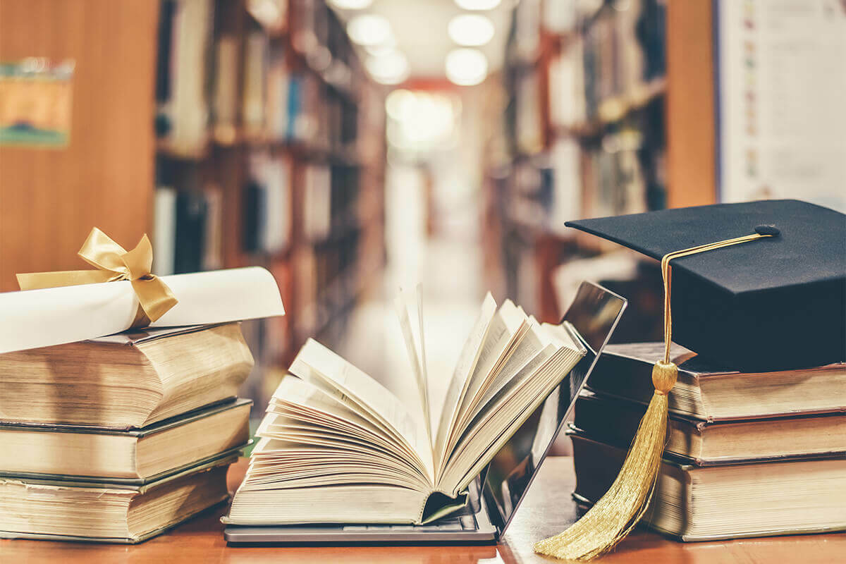 graduation cap and diploma sitting on top of Criminal Justice books in a library