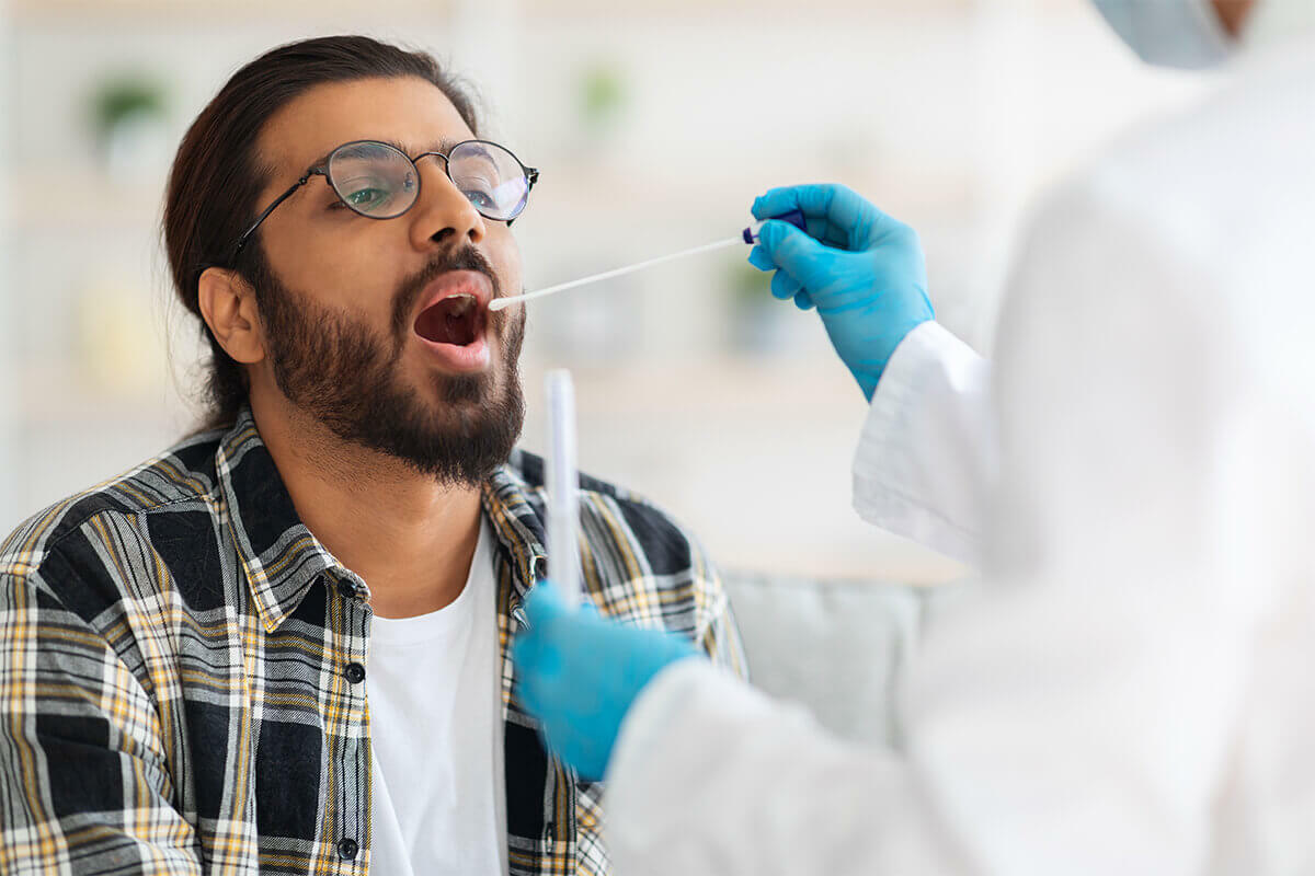 lab technician using a swab to collect oral fluid for testing