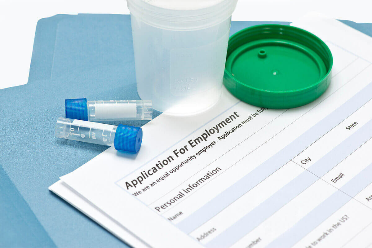 drug testing receptacles sitting on top of an application for employment