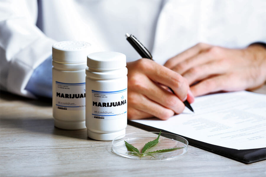 Doctor writing on prescription blank and bottle with medical cannabis on table close up