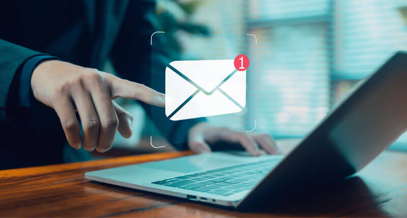 business professional touching floating email notification icon above laptop