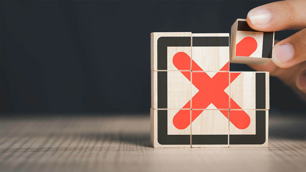 hand stacking wooden blocks with a bold red x painting