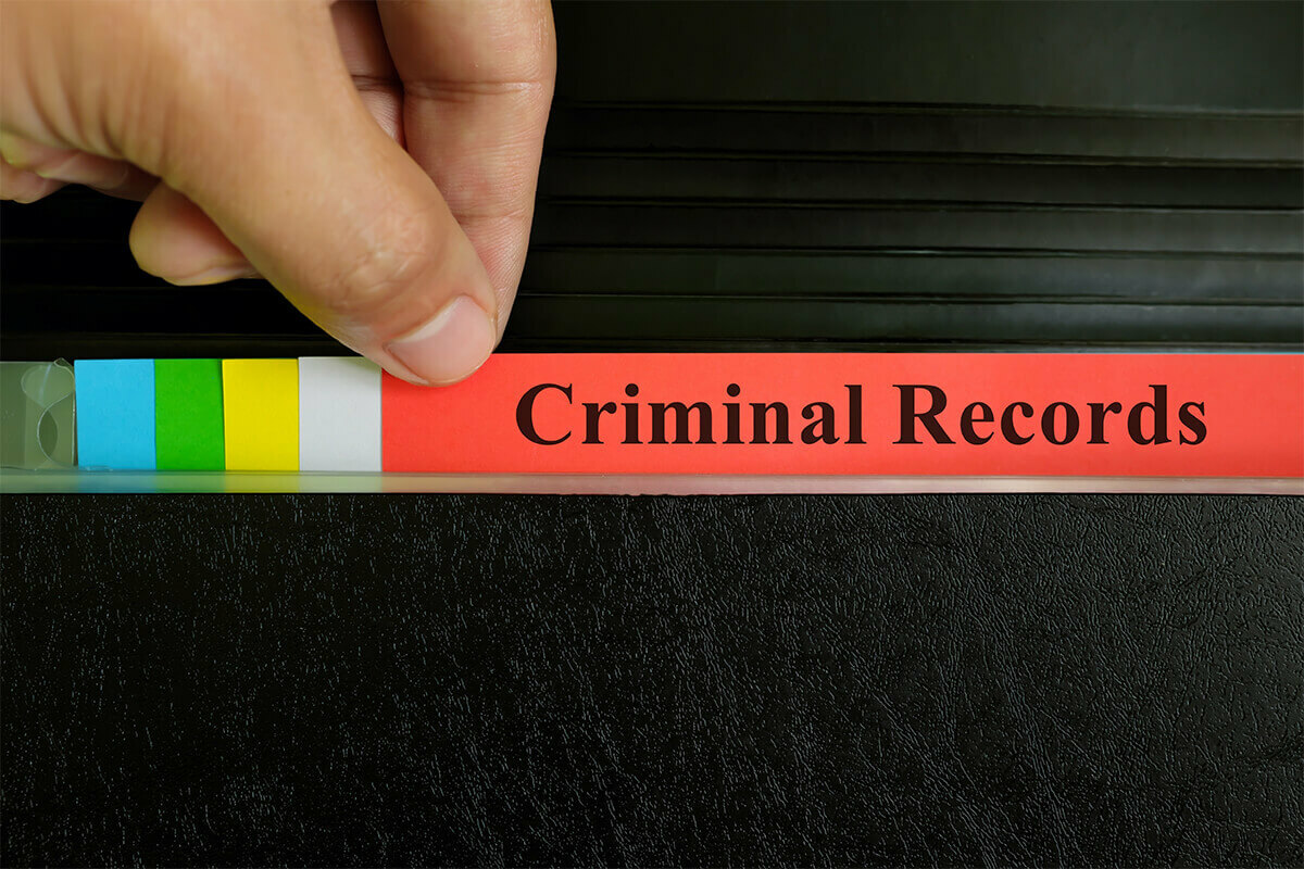Hand pulling file folders that are titled Criminal Records
