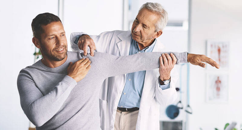 Doctor, man and patient in healthcare for shoulder pain