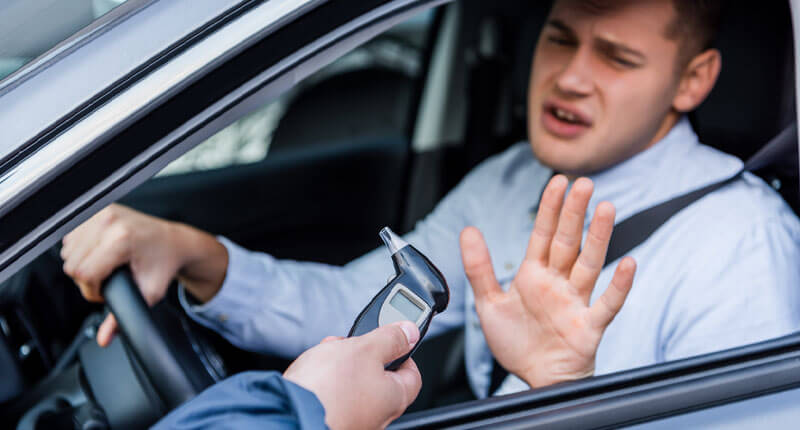 policeman giving breathalyzer to drunk driver showing refuse gesture,