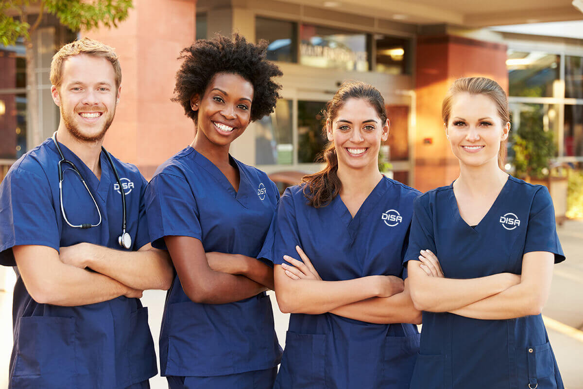 4 nurses wearing DISA scrubs standing together with arms crossed