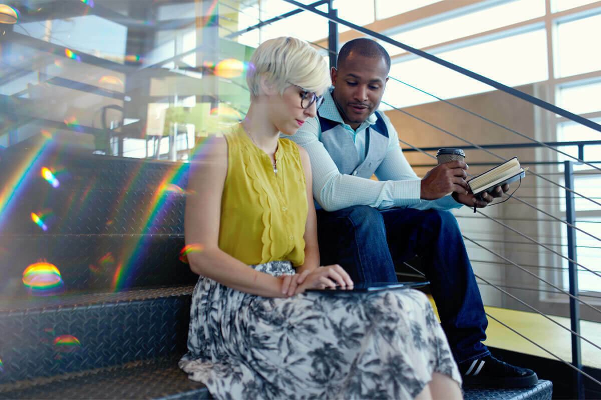Coworkers sitting on stairs looking at a tablet together