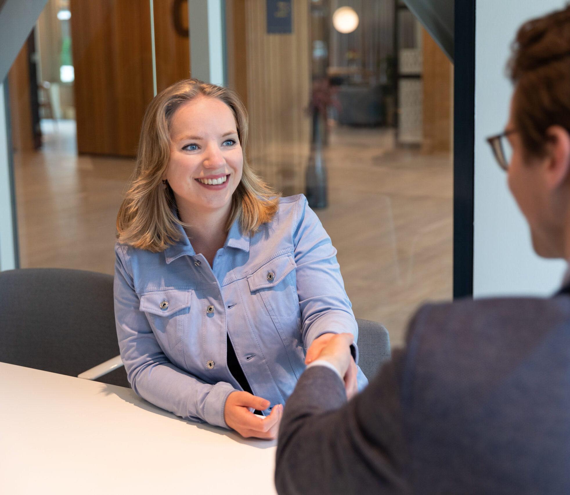 Glad kvinna skakar hand med ung affärsman