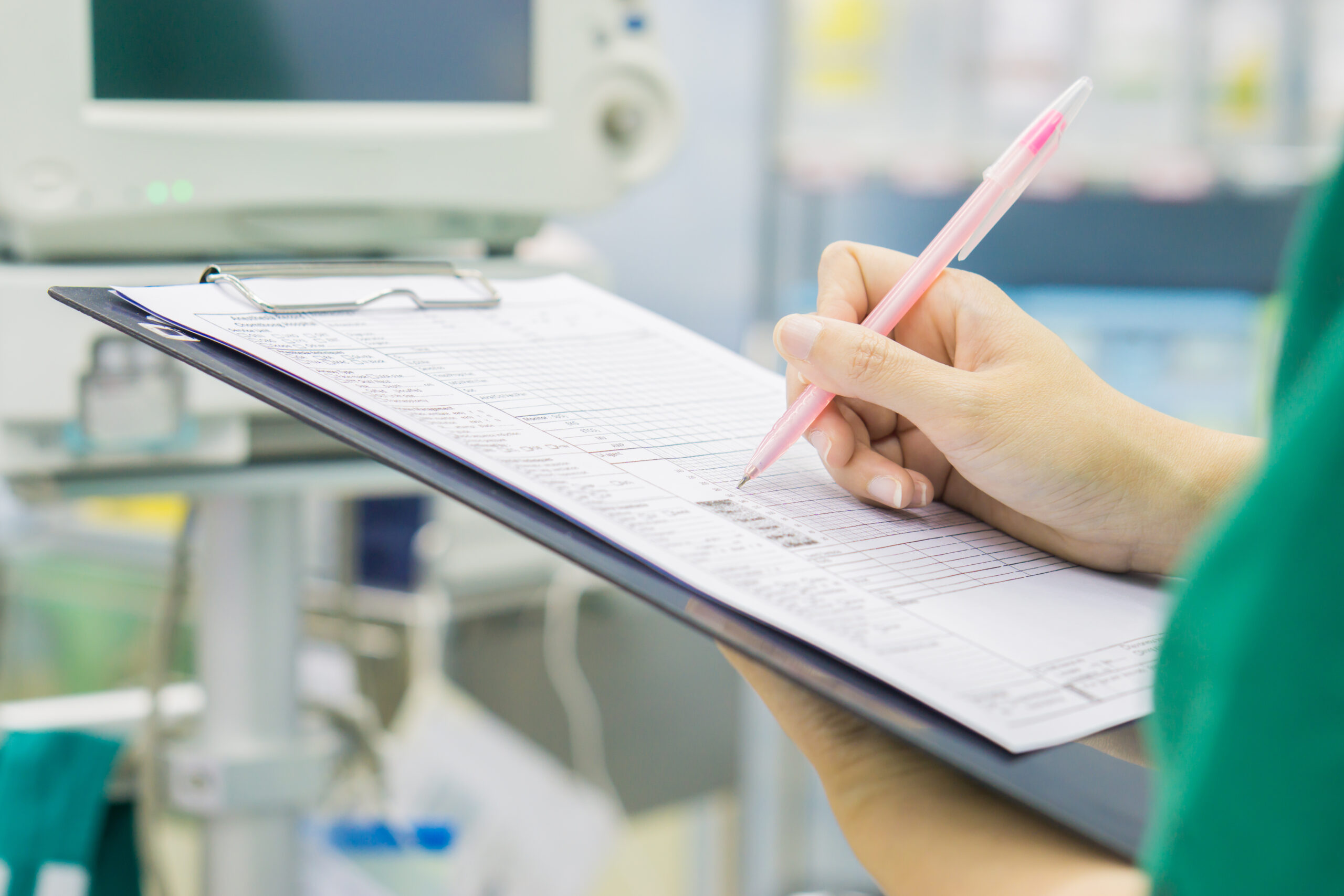 healthcare worker writing on a document on a clipboard