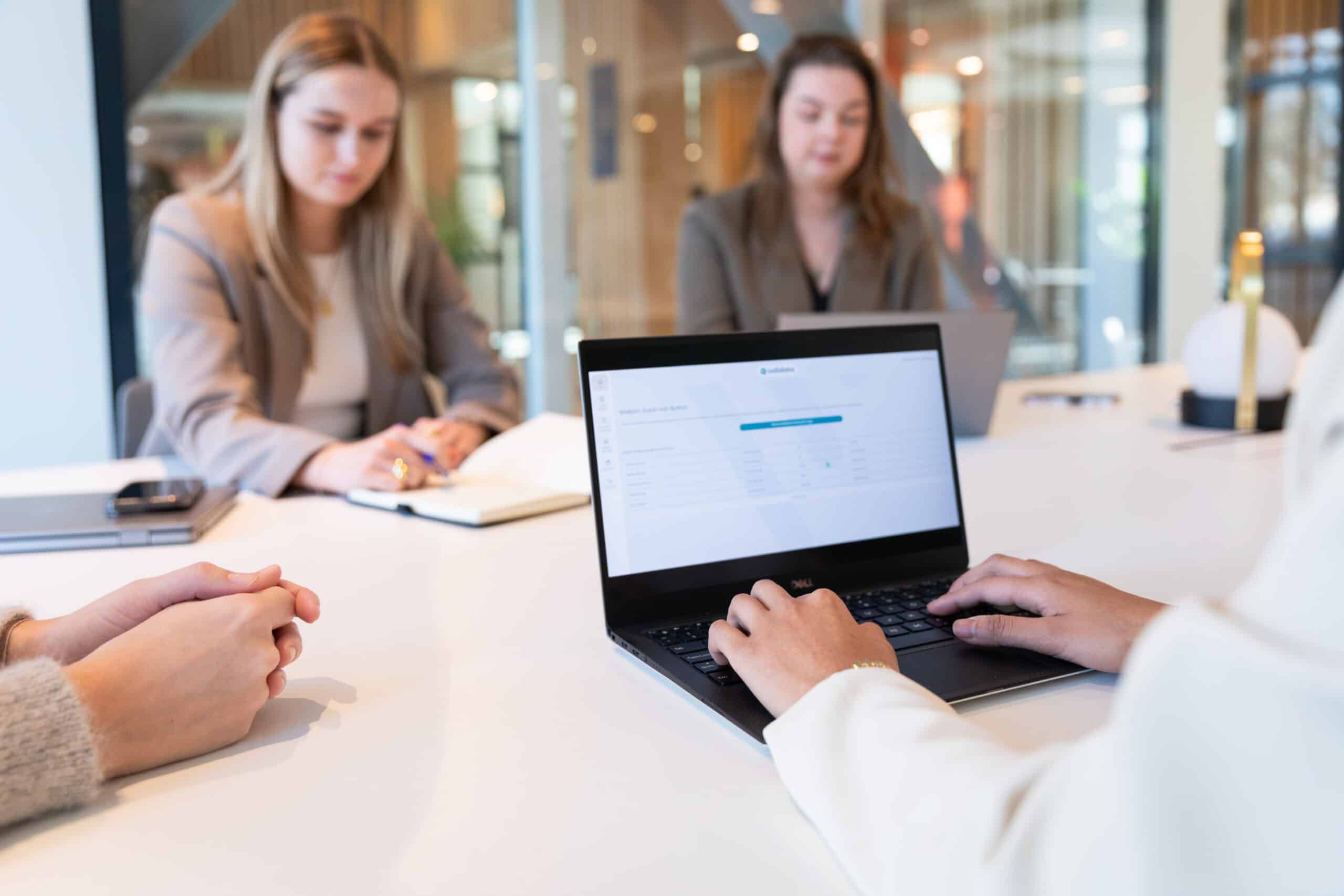 Een hand houdt een lichtgevende sci-fi wereldbol vast met blauwe iconen eromheen, terwijl de andere hand een computer bedient