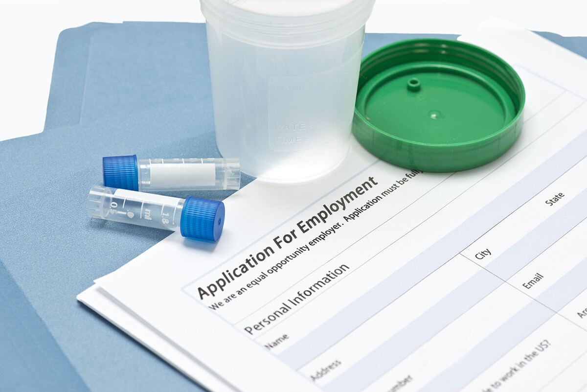 Drug test specimen collection containers sitting on an employment application