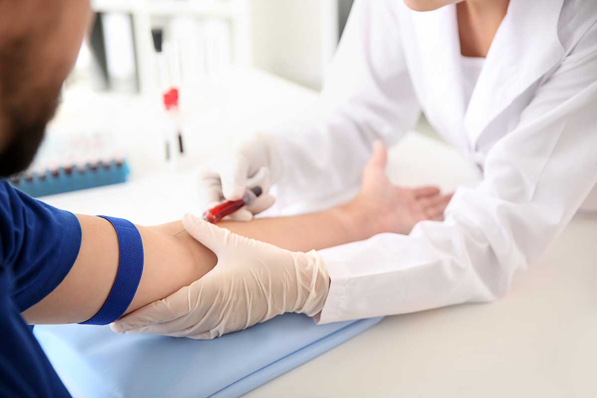 Female occupational health doctor drawing a blood sample of male patient in clinic