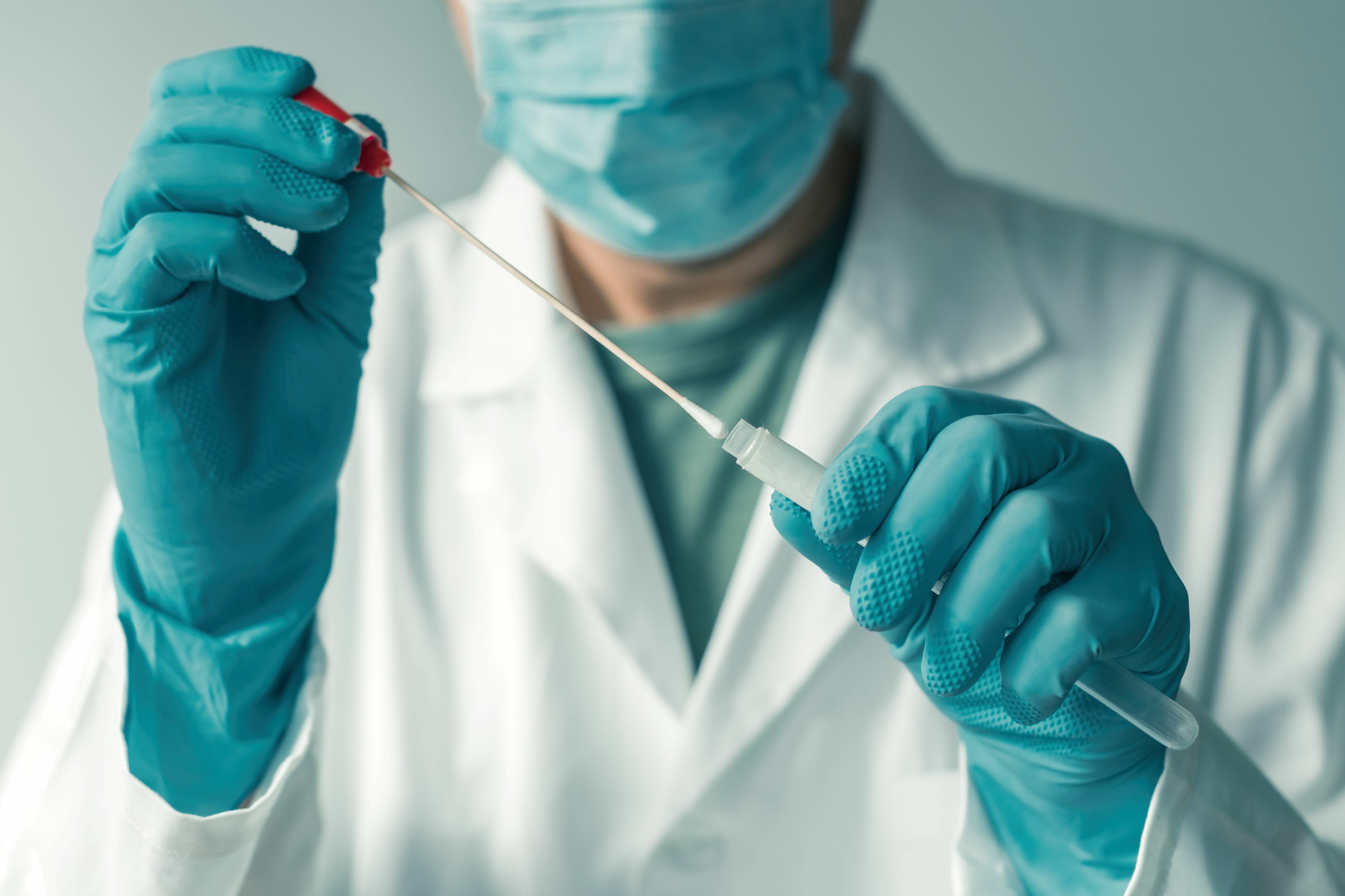 medical technician putting a swab with oral fluid into a test tube