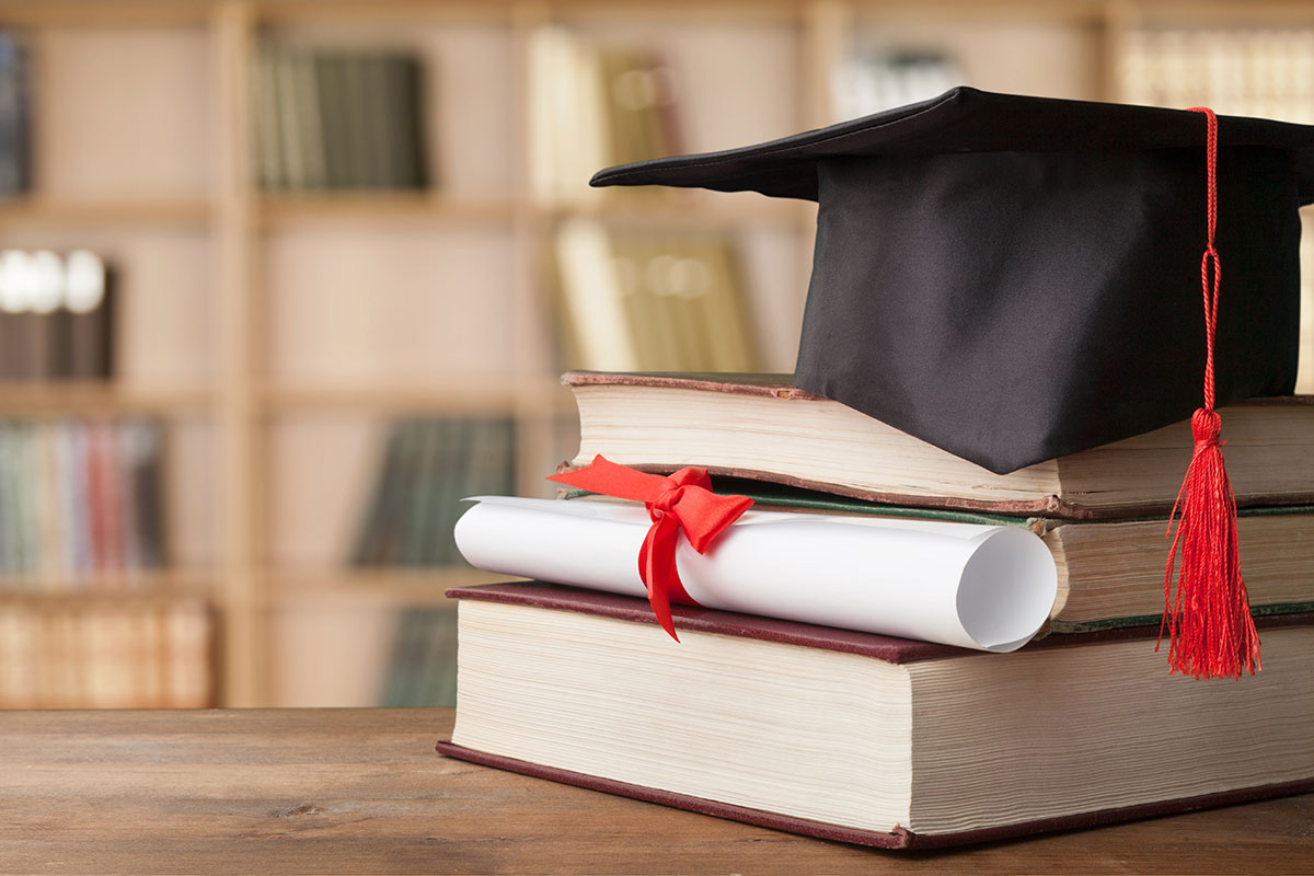 stack of book with a graduation hat and diploma