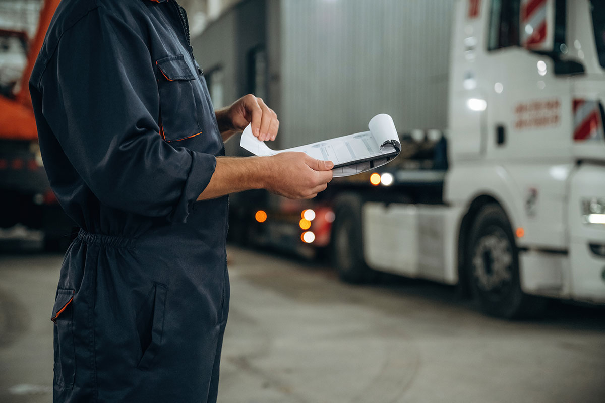 transportation operator reviewing permits standing next to large truck