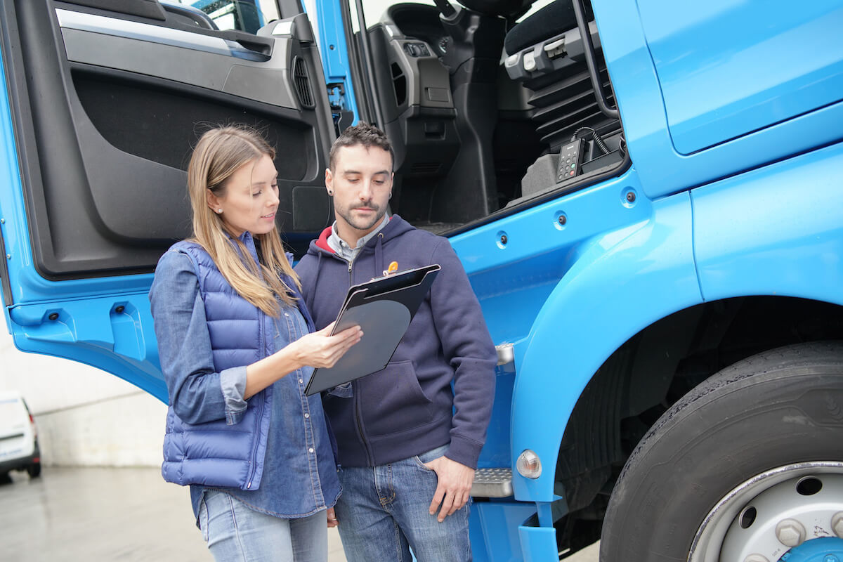 Transportation compliance worker reviewing a clipboard with a driver
