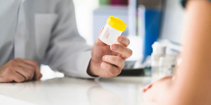 man giving a drug test specimen container to a patient