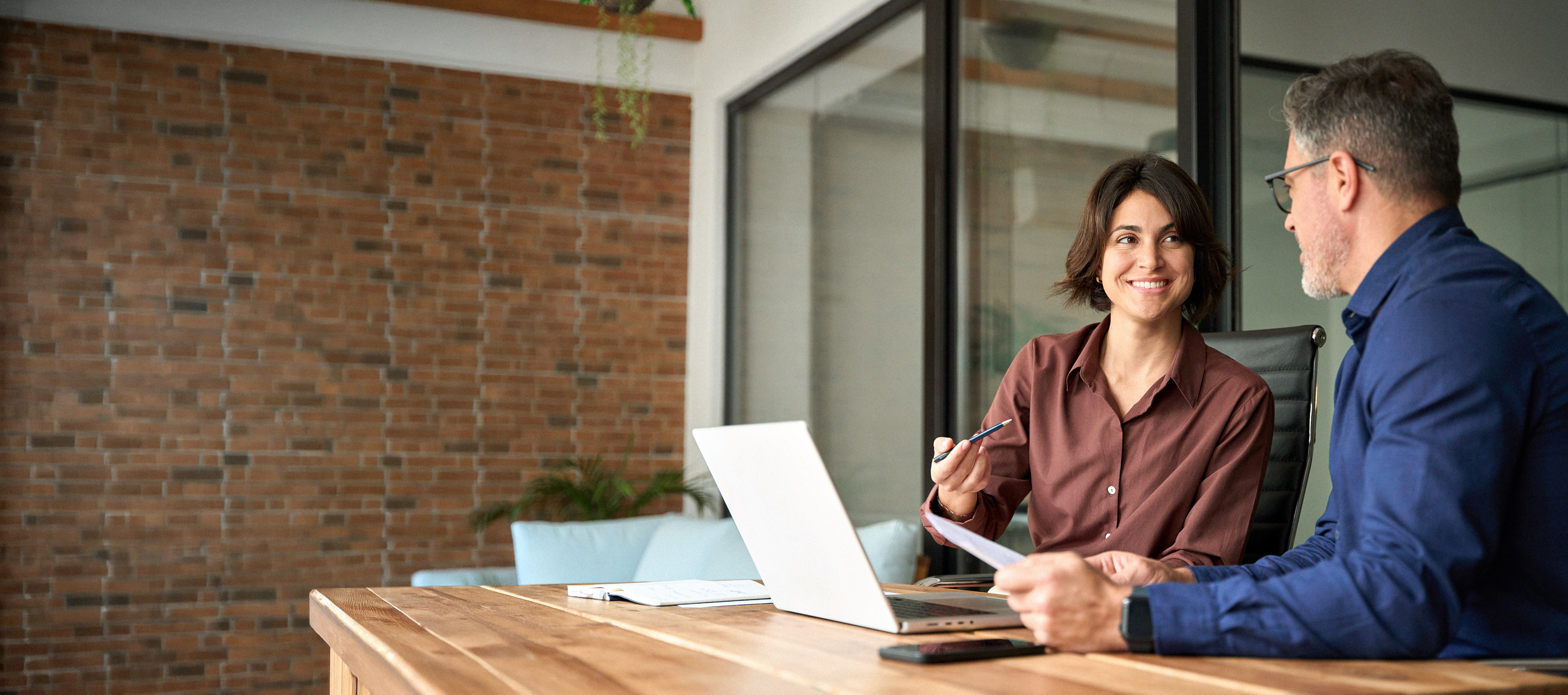 Man and woman working on laptop discussing documents in meeting