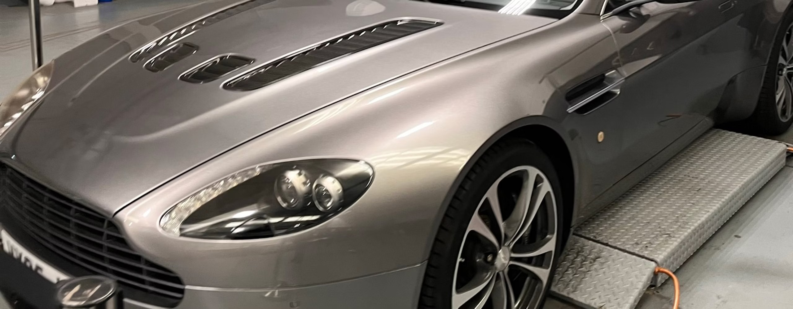 An Aston Martin on a ramp in a workshop
