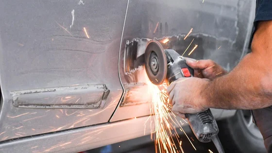 A person working on the body work of a car door
