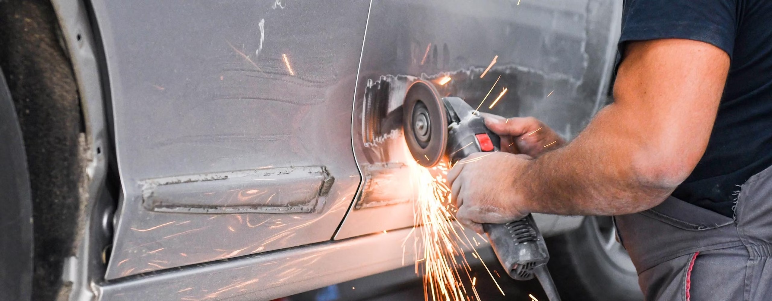 A person working on the body work of a car door