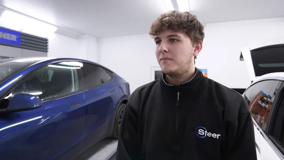A motor vehicle stood smiling in a workshop