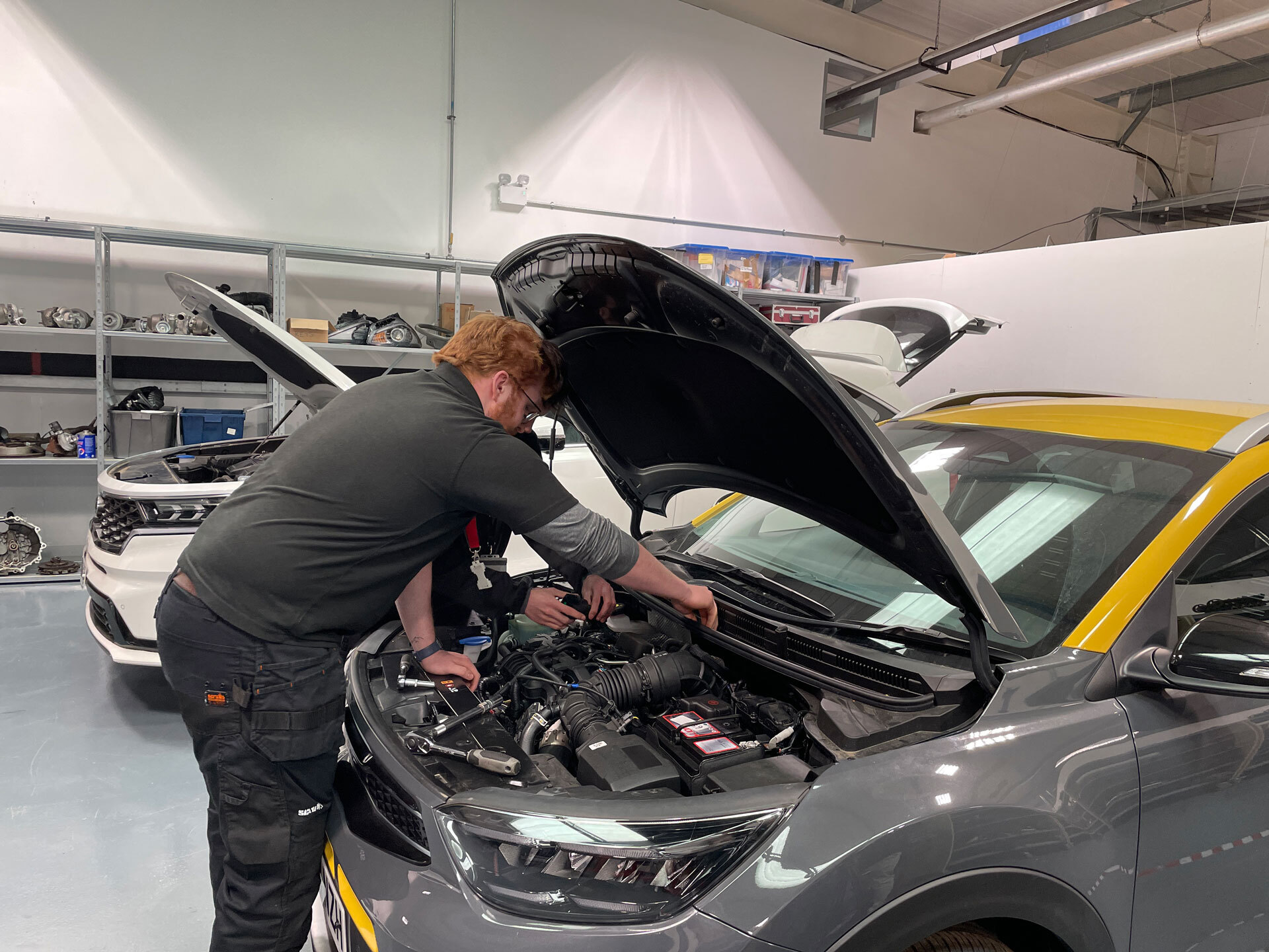 A motor Vehicle student looking into a cars bonnet to fix something