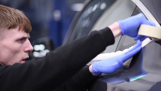 A student working on the body of car.