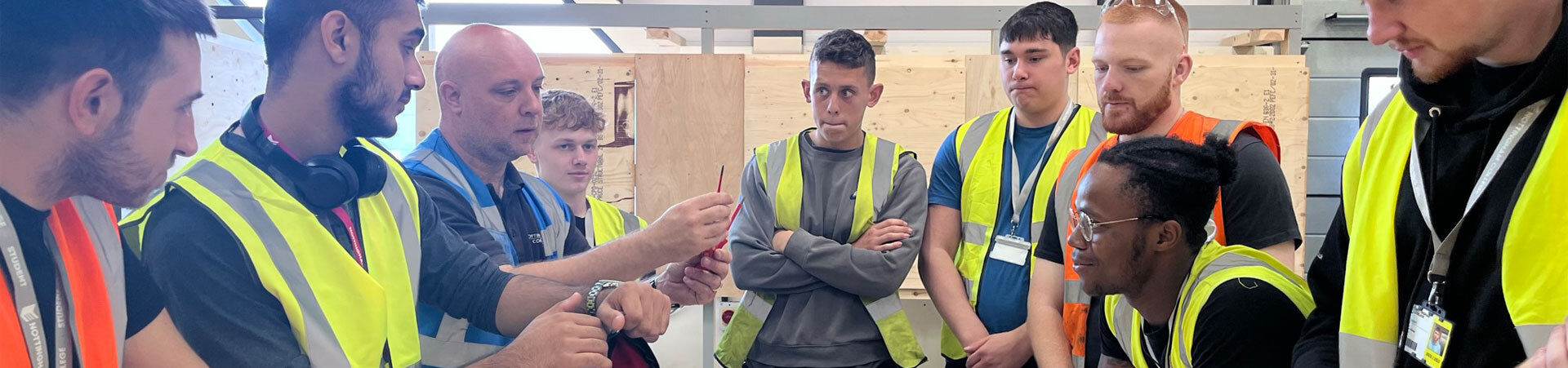 A group of construction students listening to their tutor explain something