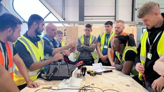 A lecturer teaching a group of apprenticeships in a construction workshop.
