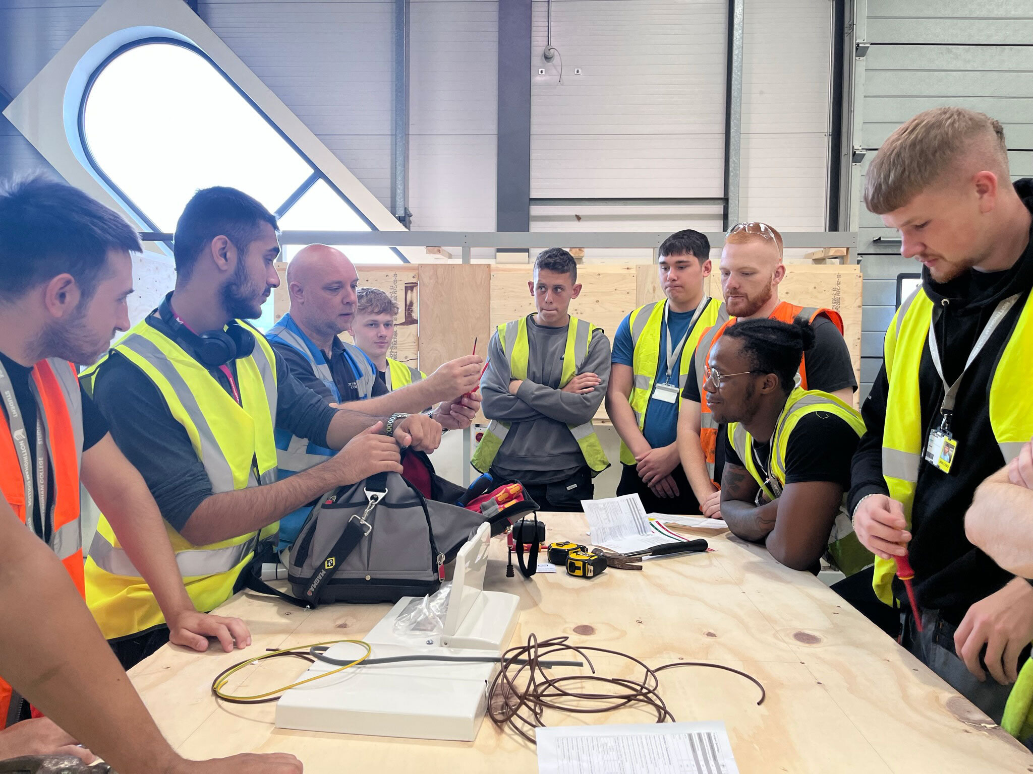 A lecturer teaching a group of apprenticeships in a construction workshop.