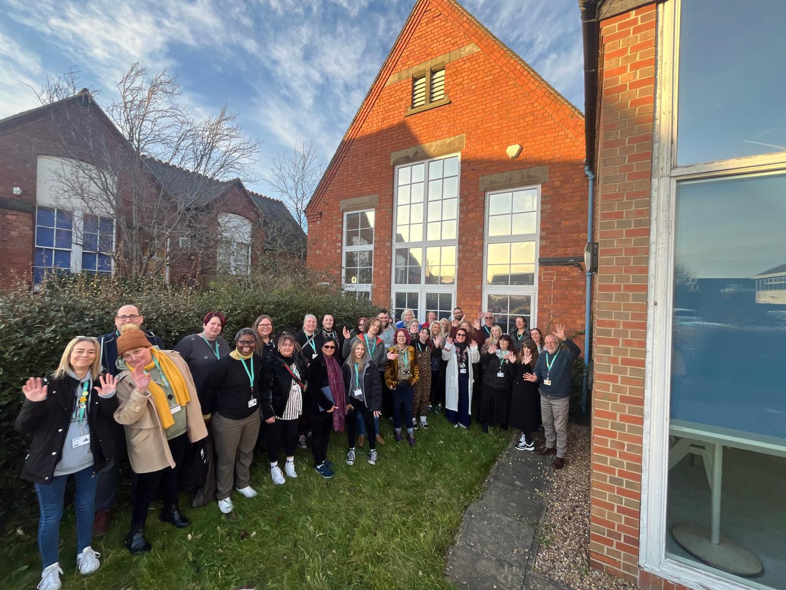 Members of staff outside a campus stood in a large group next to the building.