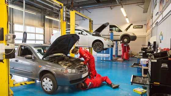 Students working on cars in a garage workshop