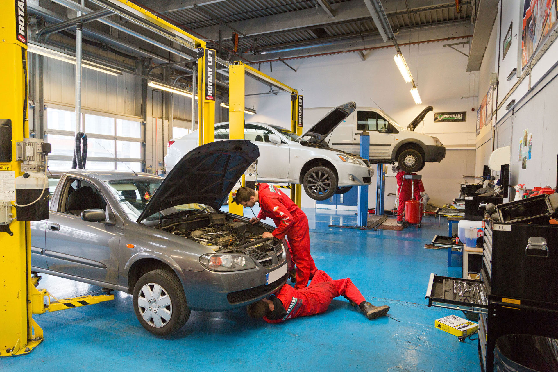 Students working on cars in a garage workshop