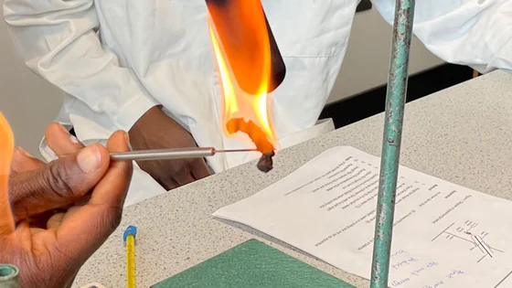 Two students working in a science lab using a Bunsen burner
