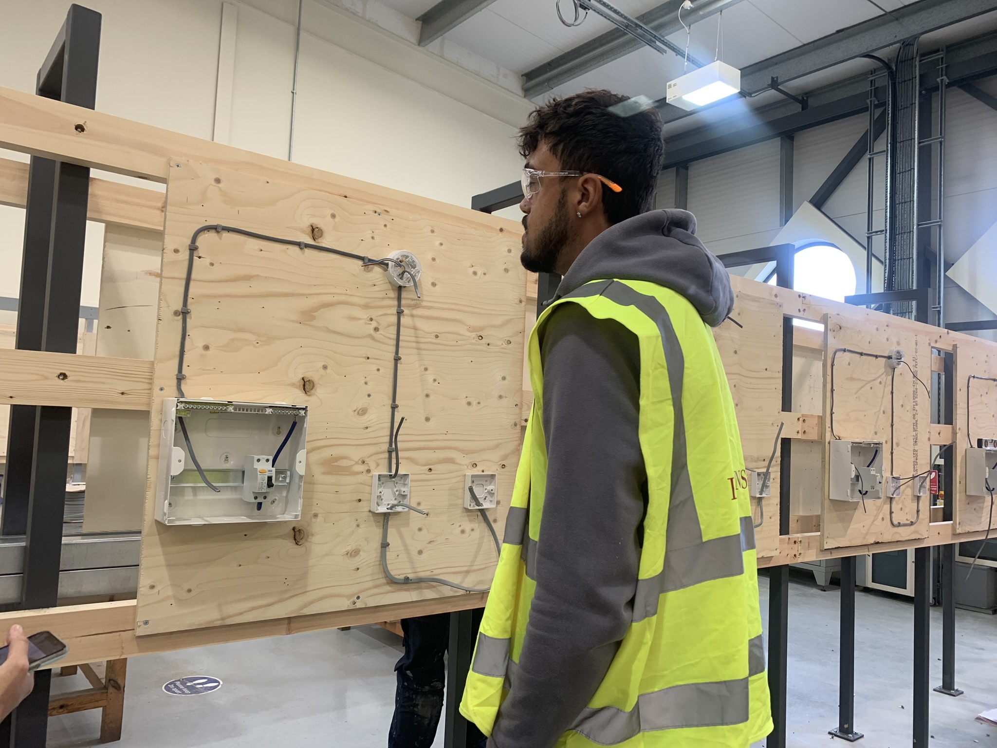 A student looking at a wiring job on a wall.