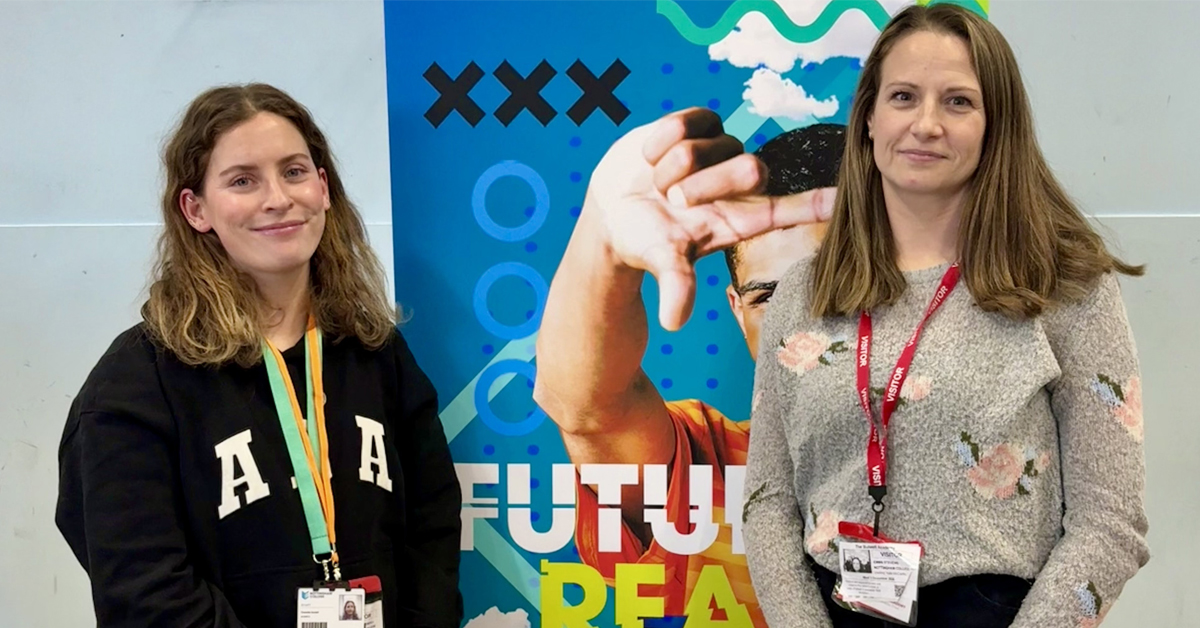 Emma and Charlotte standing in front of a banner at a careers fair