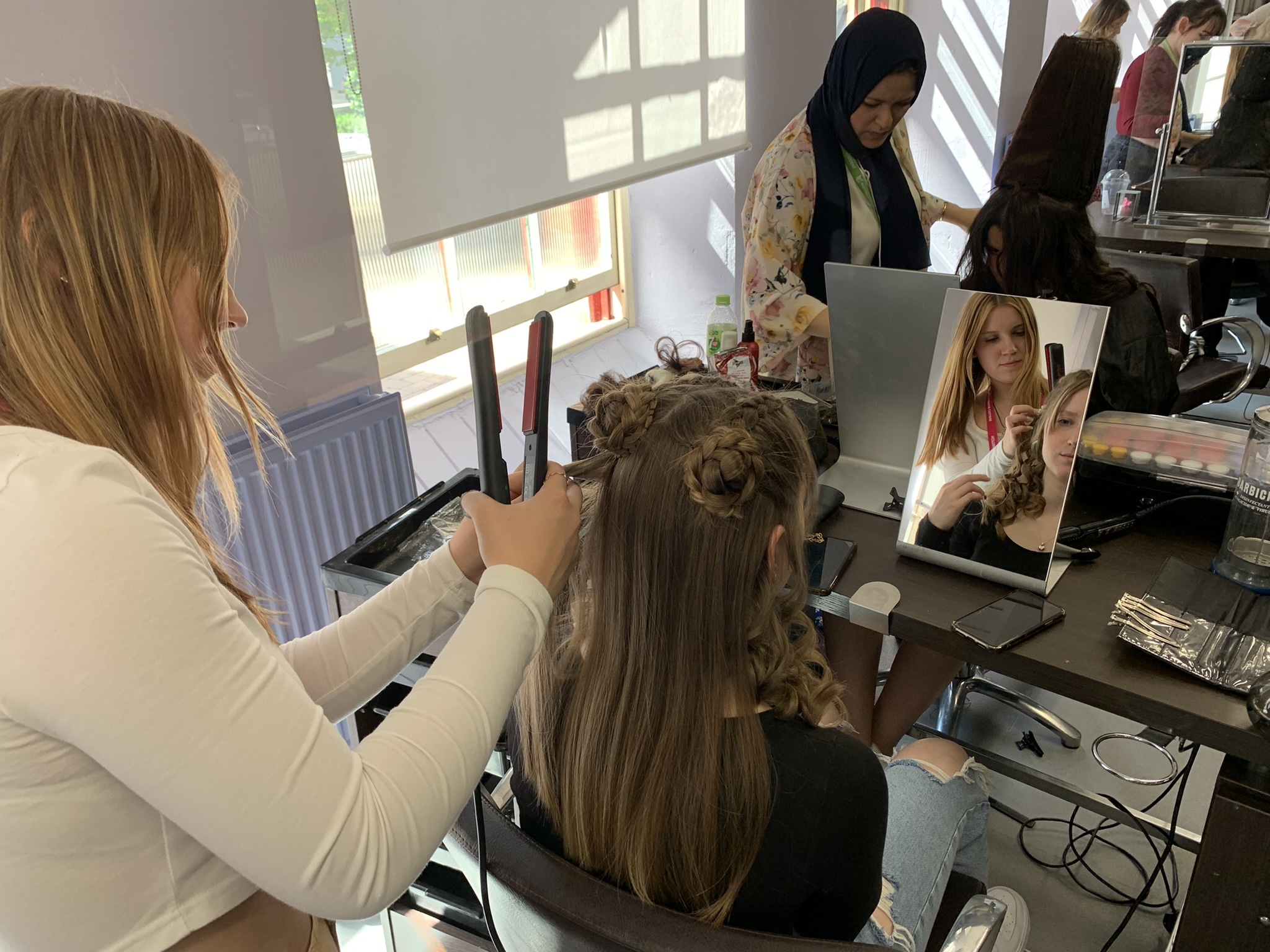A student styling a client's hair in a salon at the Adams Building