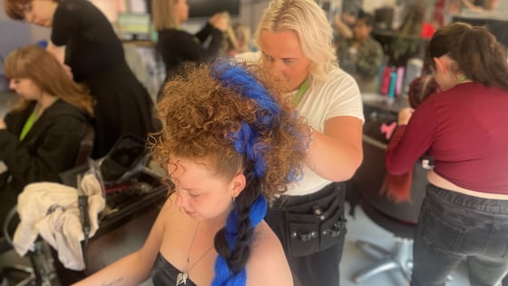 A student styling someone's hair in the hair salon